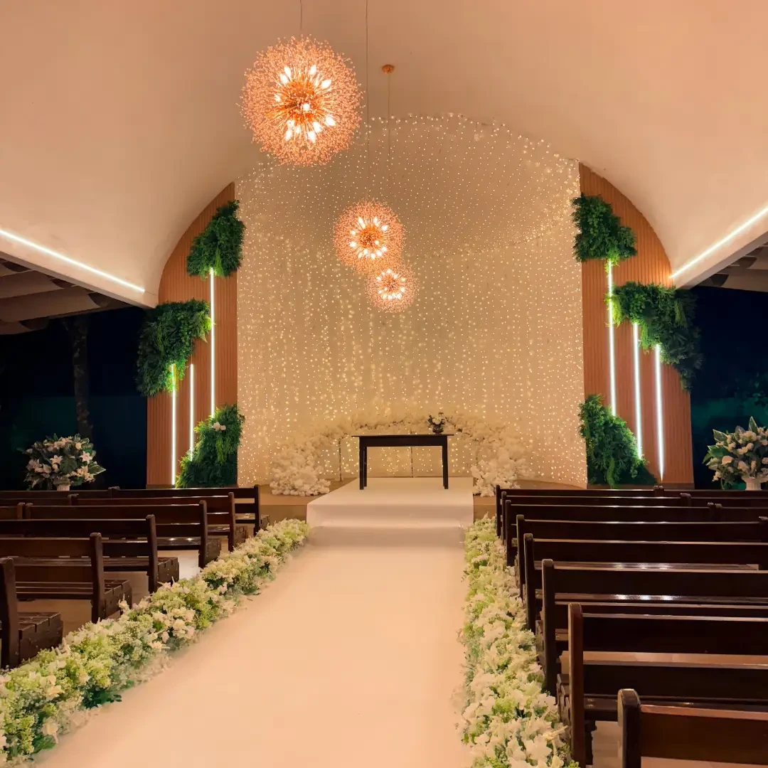 Capela interna do Villa Borghese, com corredor de flores, altar, lustres e cortina de luzes